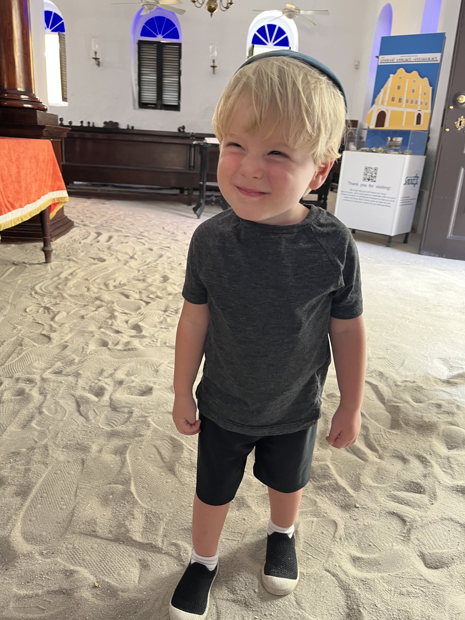 Child standing on the sand-covered floor inside the synagogue