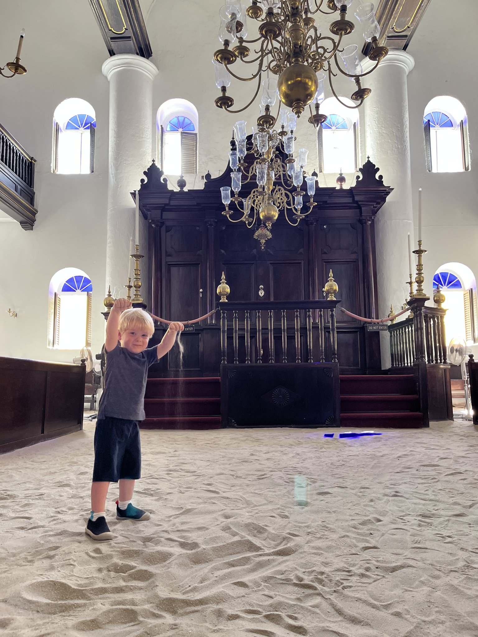 Interior of the Mikvé Israel-Emanuel Synagogue showing its sand floor, bimah and chandeliers